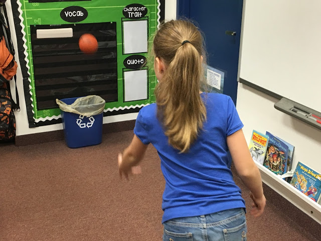 girl with ponytail and blue shirt playing trashetball with task cards for test prep
