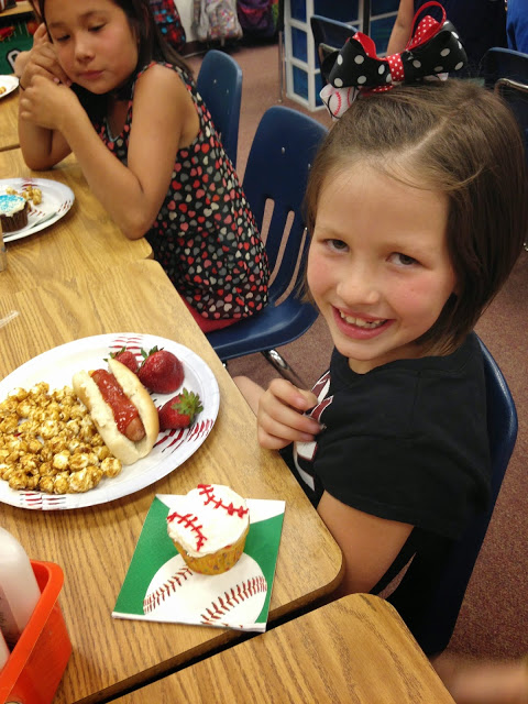 Little girl smiling with hotdog, strawberries, cracker jacks and cupcake at a post testing party