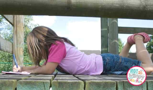Girl in pink t-shirt and denim skirt lying on her belly outside writing